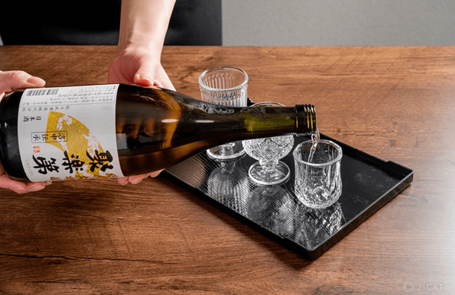 Staff pouring sake into a small cup during tasting at Sasaki Brewery in Kyoto