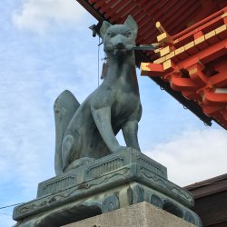 Stone fox statue holding a key at Fushimi Inari Taisha in Kyoto
