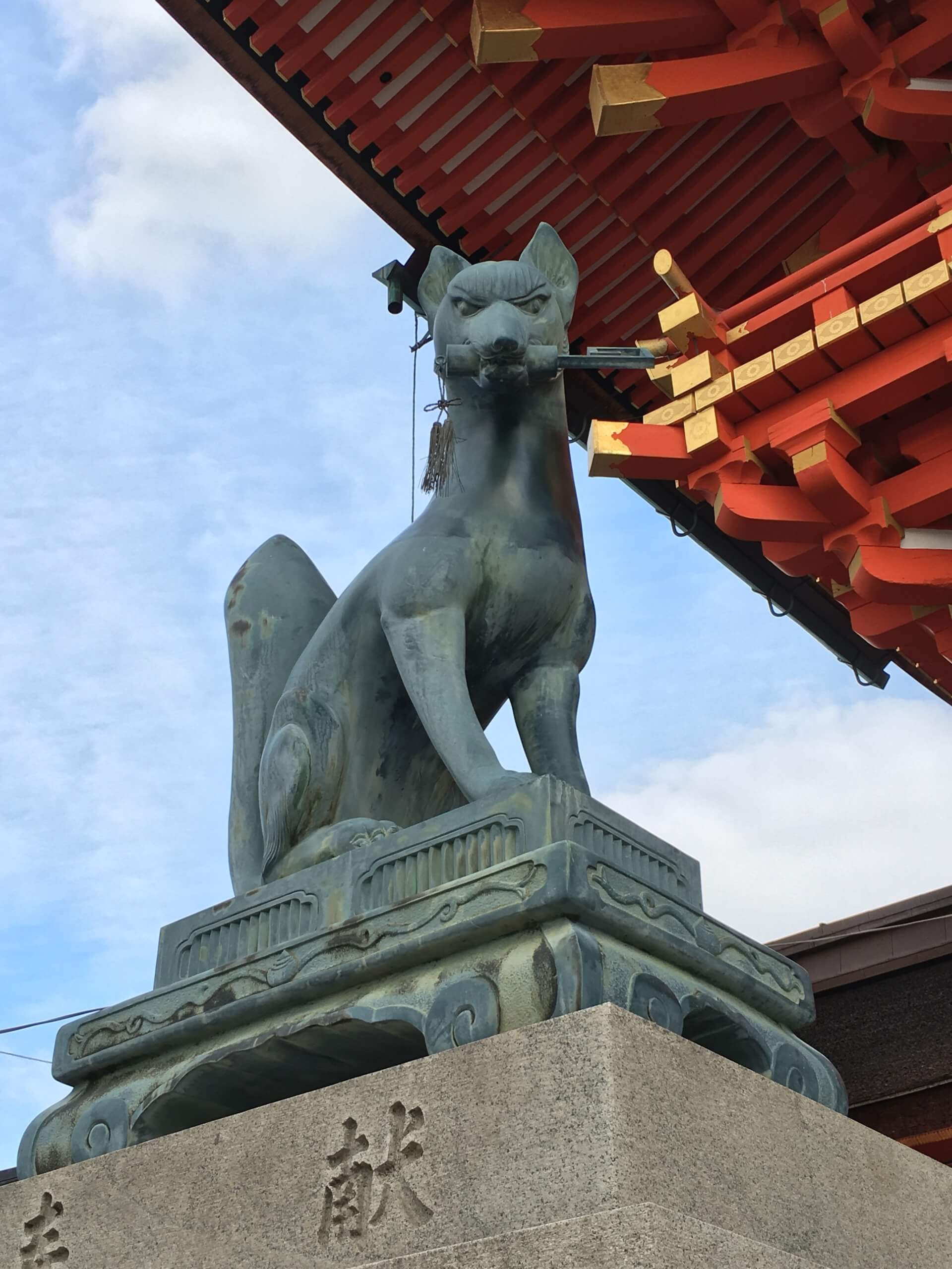 Stone fox statue holding a key at Fushimi Inari Taisha in Kyoto